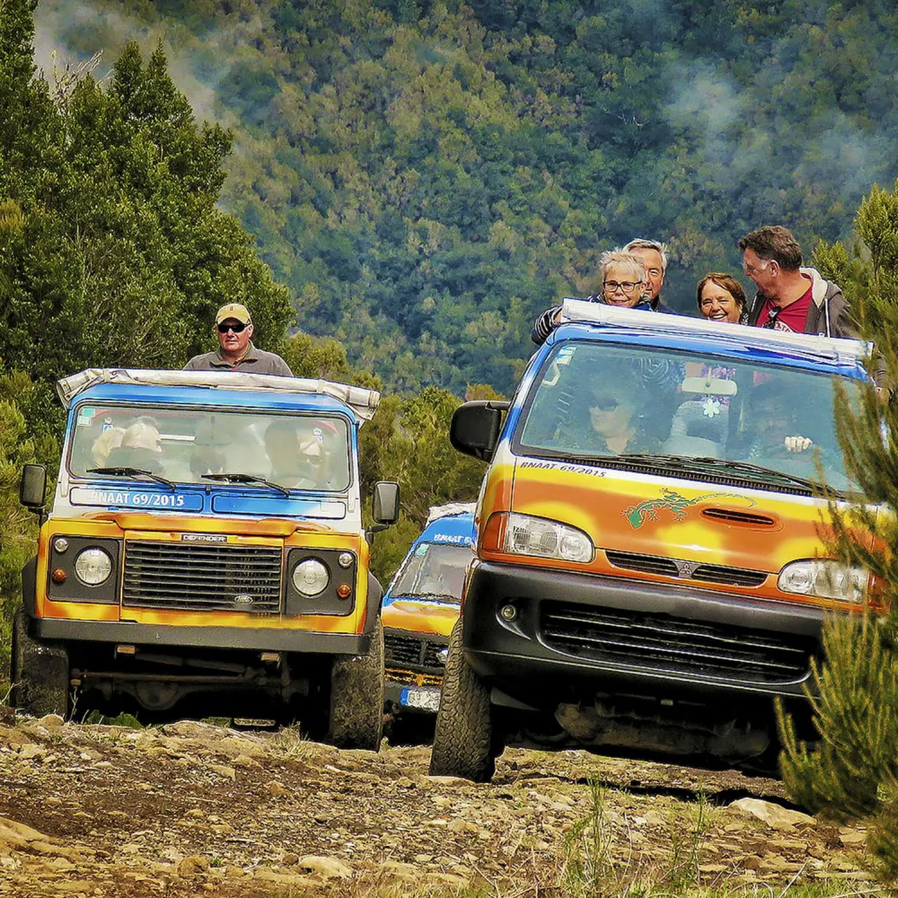 Twee kleurrijke jeeps met reizigers op een bergweg tijdens een jeepsafari op Madeira