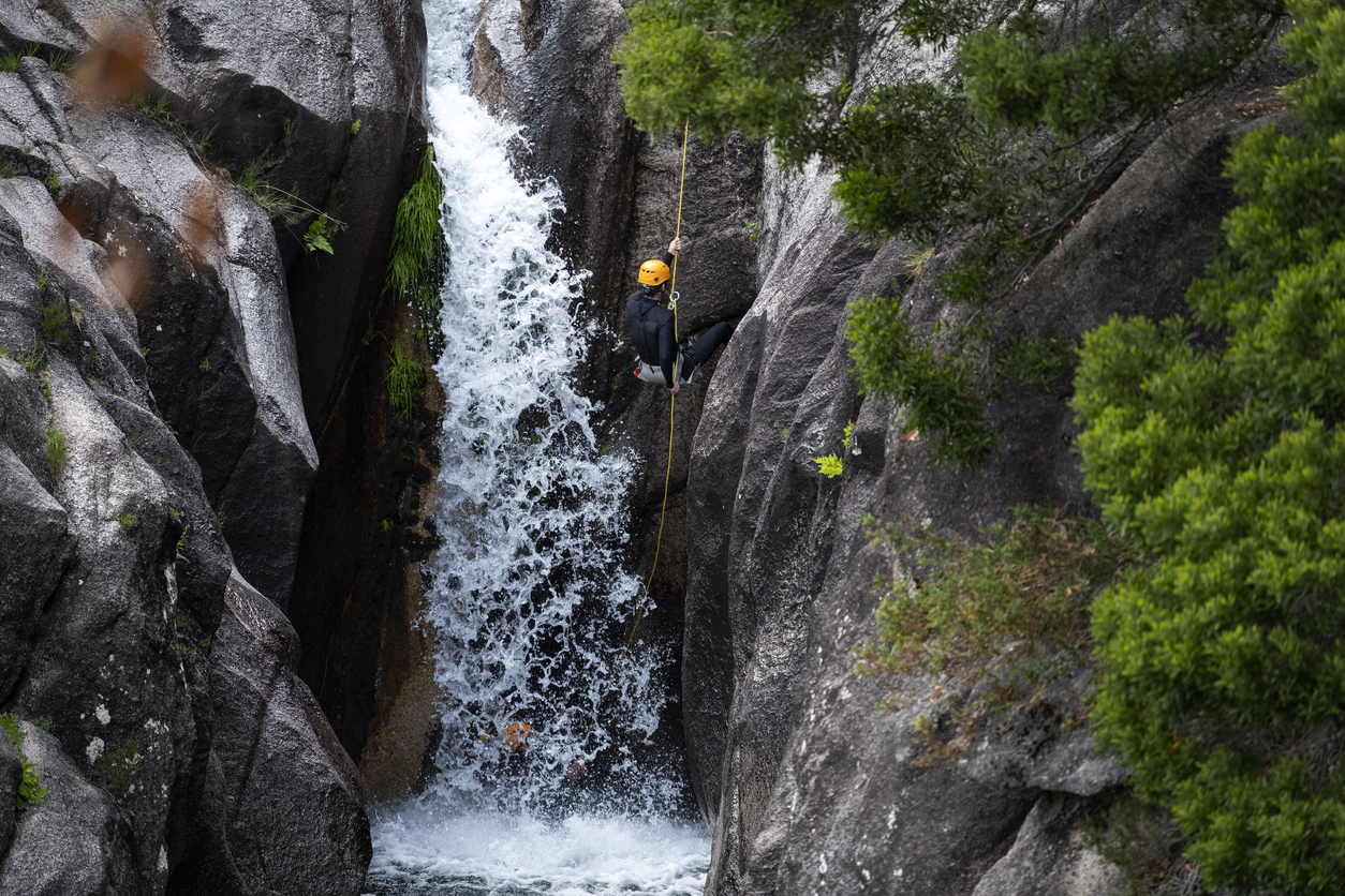 Man daalt abseilend af langs een waterval