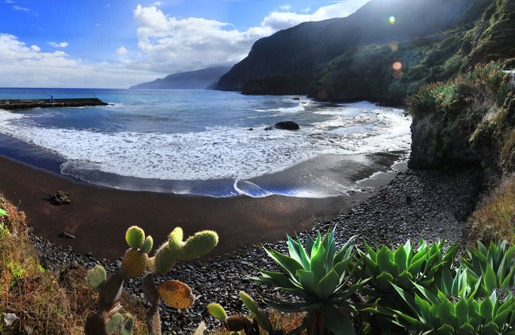 Zwart zandstrand van Seixal met groene bergen op Madeira